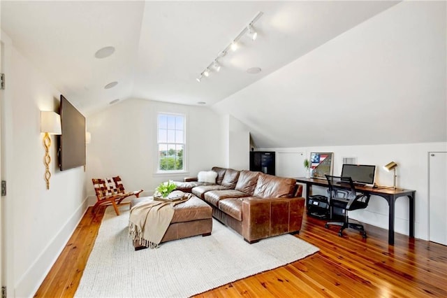 living area featuring rail lighting, baseboards, lofted ceiling, and hardwood / wood-style flooring