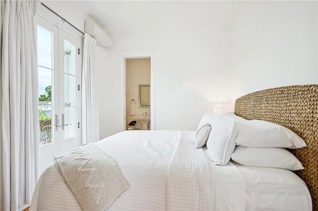 bedroom featuring french doors, ensuite bath, and a wall mounted AC