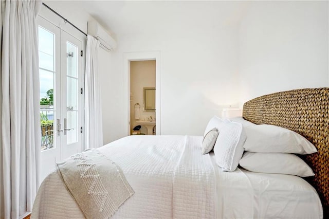 bedroom with french doors, ensuite bathroom, and a wall unit AC