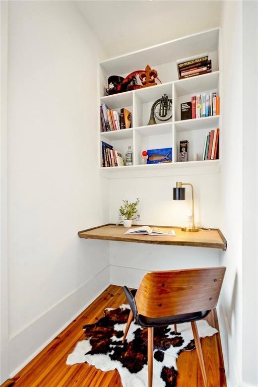 office area with baseboards, wood finished floors, and built in desk