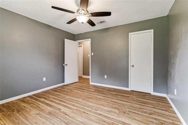 unfurnished bedroom with light hardwood / wood-style flooring, a textured ceiling, and ceiling fan