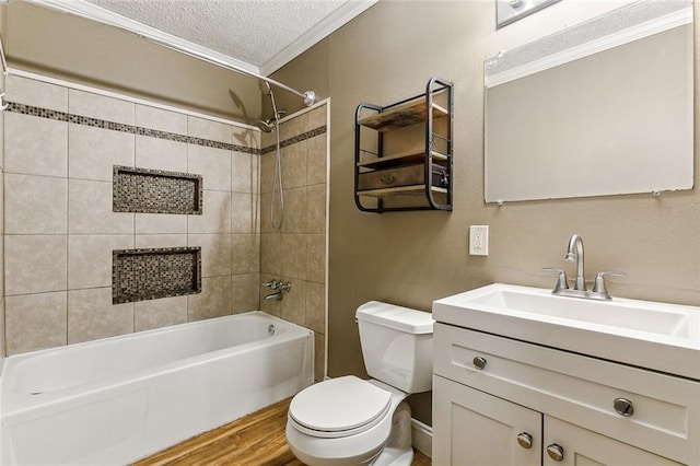 full bathroom with a textured ceiling, toilet, vanity, crown molding, and tiled shower / bath combo