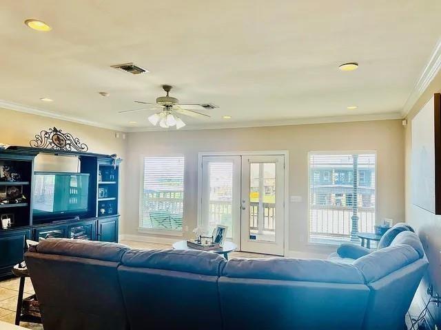 tiled living room with ceiling fan, french doors, and ornamental molding