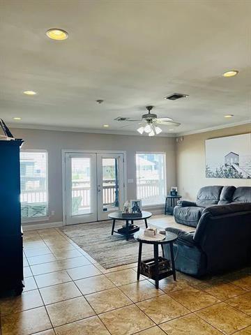 tiled living room featuring plenty of natural light, ceiling fan, ornamental molding, and french doors