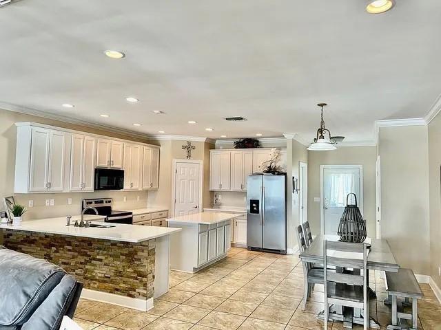 kitchen featuring pendant lighting, a kitchen island, ornamental molding, and appliances with stainless steel finishes