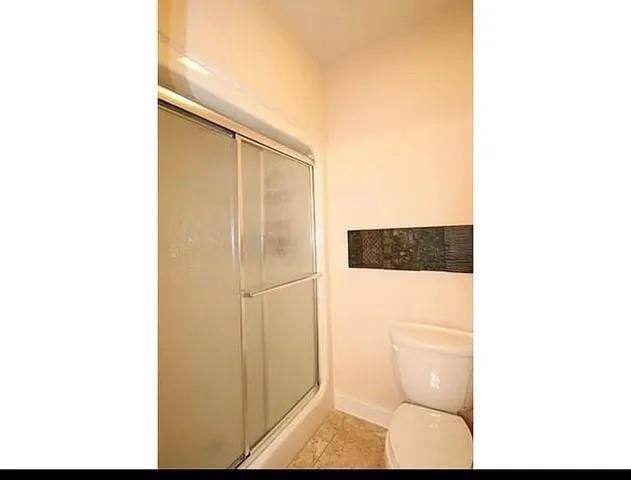 bathroom with tile patterned floors, toilet, and walk in shower