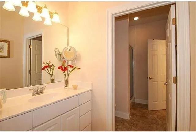 bathroom with tile patterned flooring, vanity, and a shower with door