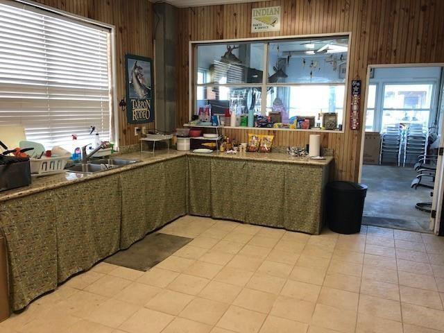 kitchen featuring sink, light colored carpet, and wood walls