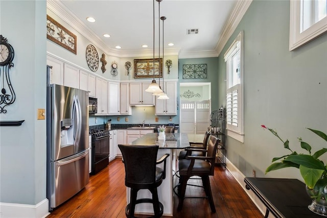 kitchen featuring black appliances, a center island, sink, hanging light fixtures, and a breakfast bar area