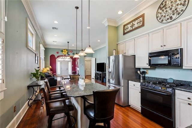 kitchen with a kitchen island, dark wood-type flooring, black appliances, a breakfast bar, and crown molding