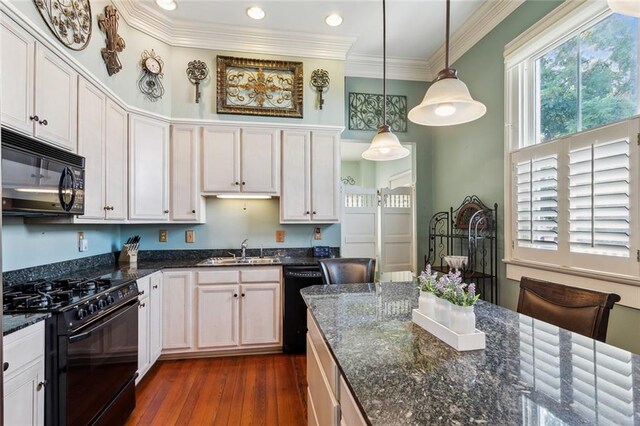 kitchen with pendant lighting, dark hardwood / wood-style flooring, sink, white cabinets, and black appliances