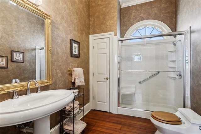 bathroom featuring toilet, crown molding, hardwood / wood-style floors, sink, and a shower with door