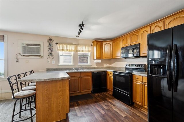 kitchen with dark hardwood / wood-style flooring, a breakfast bar, kitchen peninsula, a wall mounted air conditioner, and black appliances