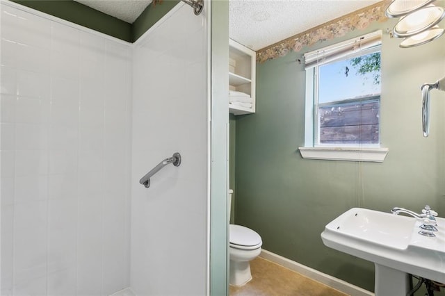 bathroom with sink, a textured ceiling, a shower, tile patterned floors, and toilet