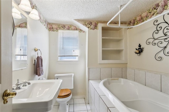 bathroom featuring tile patterned flooring, toilet, sink, a relaxing tiled tub, and a textured ceiling