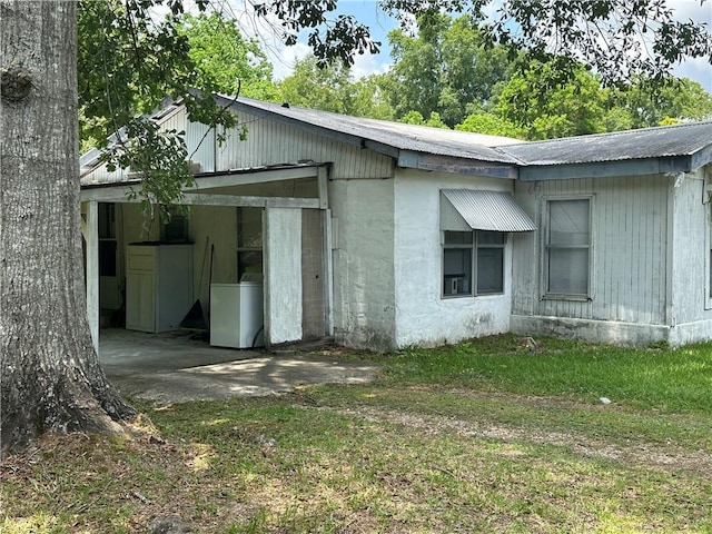 view of side of property featuring washer / dryer and a lawn