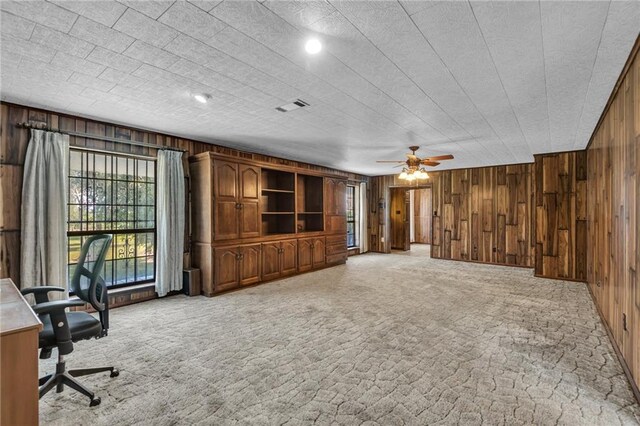 unfurnished living room featuring wood walls, carpet flooring, and ceiling fan