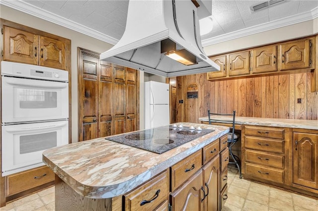 kitchen featuring wood walls, white appliances, island range hood, a center island, and crown molding