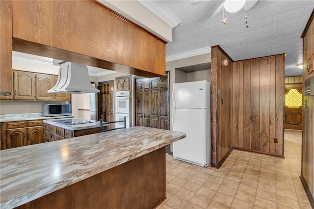 kitchen featuring ceiling fan, white appliances, island range hood, ornamental molding, and a center island