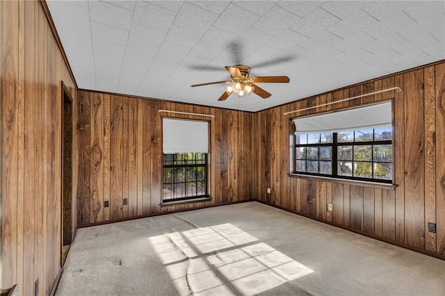 carpeted spare room featuring ceiling fan and wooden walls