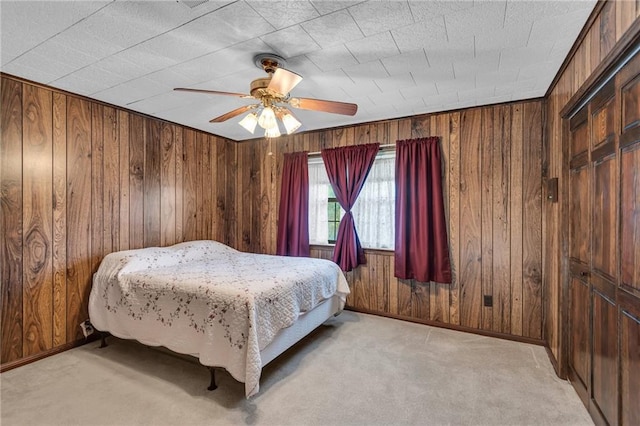 carpeted bedroom with ceiling fan, a closet, and wood walls