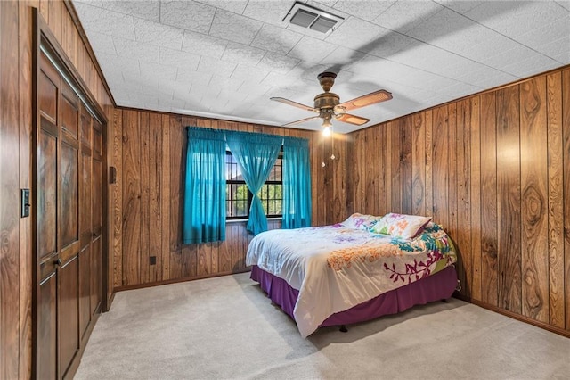 carpeted bedroom featuring a closet, wooden walls, and ceiling fan