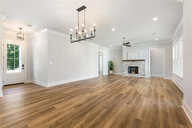 unfurnished living room with a fireplace, ornamental molding, ceiling fan with notable chandelier, and hardwood / wood-style floors