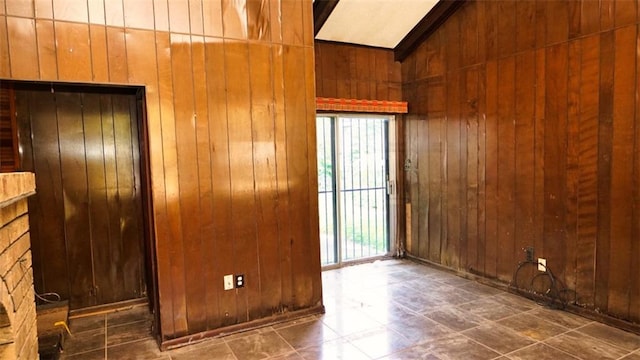 unfurnished room featuring vaulted ceiling, wooden walls, and a stone fireplace