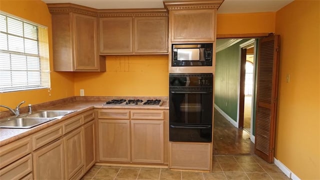 kitchen with light brown cabinetry, black appliances, sink, and light tile patterned floors