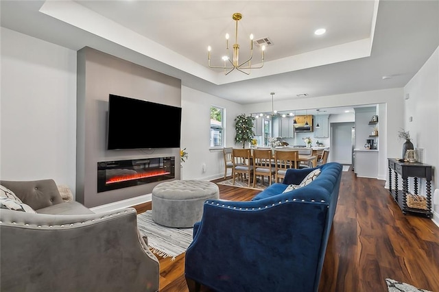 living room featuring a raised ceiling, a chandelier, and hardwood / wood-style floors