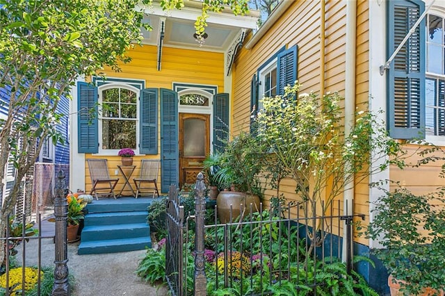 view of exterior entry with a porch and fence