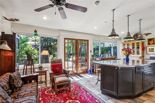 kitchen with french doors, stone tile floors, recessed lighting, stainless steel countertops, and a kitchen island