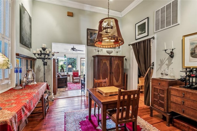 dining area with ornamental molding, visible vents, a high ceiling, and wood finished floors