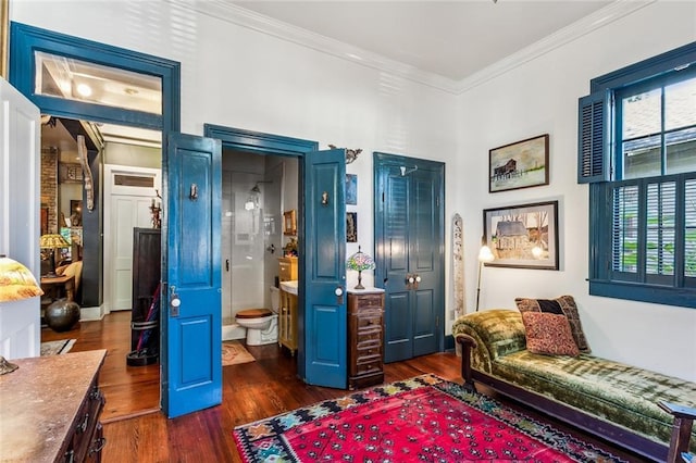 bedroom featuring dark wood-style floors, ensuite bath, and crown molding