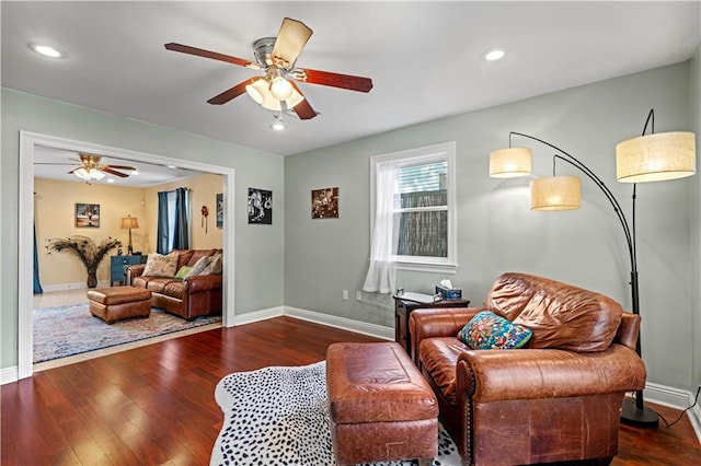 living room featuring ceiling fan and dark hardwood / wood-style floors