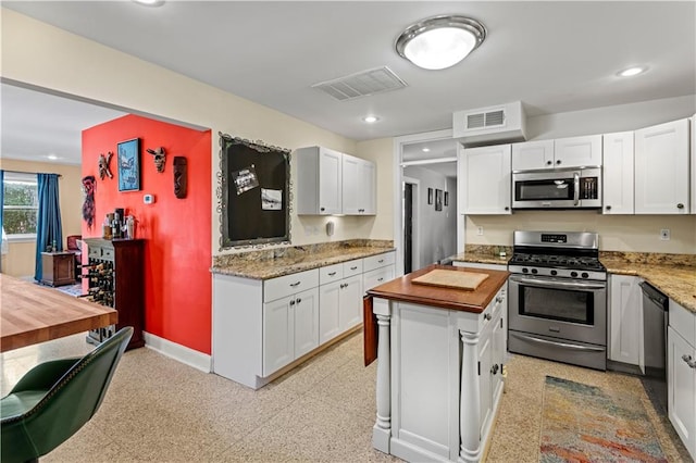 kitchen with a kitchen island, appliances with stainless steel finishes, wood counters, and white cabinetry