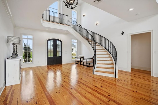 entrance foyer featuring a healthy amount of sunlight, french doors, stairs, and light wood-style floors