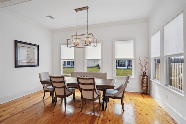 dining room with light wood finished floors, visible vents, baseboards, and ornamental molding