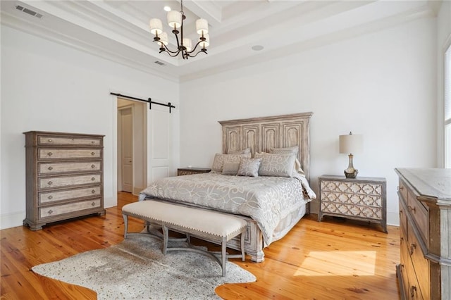 bedroom with light wood-type flooring, visible vents, a notable chandelier, coffered ceiling, and a barn door