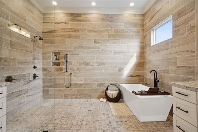 bathroom with a tile shower, a freestanding bath, and tile walls