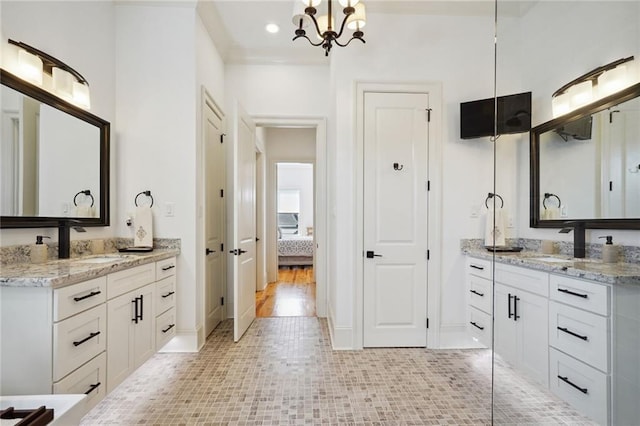 full bathroom featuring two vanities, connected bathroom, and a sink