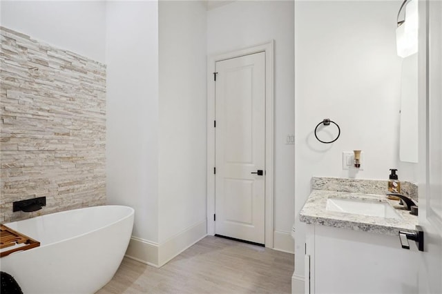 full bathroom featuring a freestanding tub, baseboards, wood finished floors, and vanity