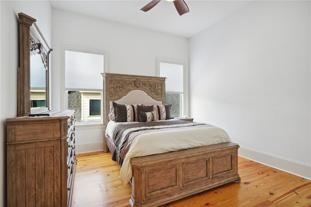 bedroom featuring baseboards, multiple windows, light wood-style floors, and a ceiling fan