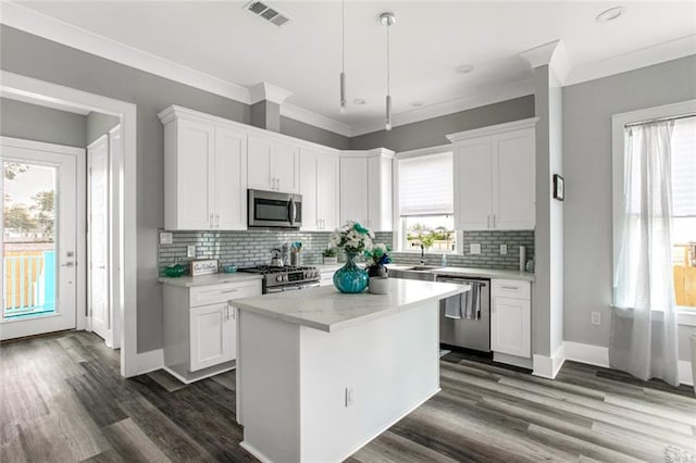 kitchen with a wealth of natural light, appliances with stainless steel finishes, and white cabinetry