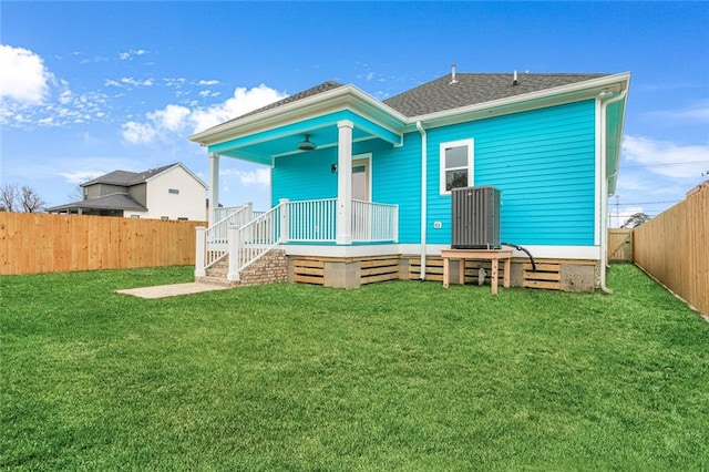 rear view of property featuring a lawn and ceiling fan