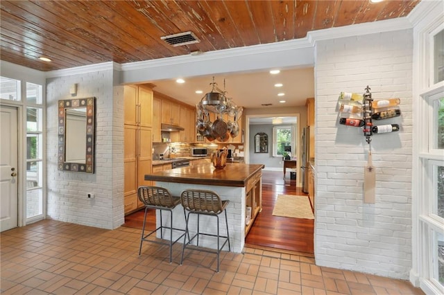 kitchen featuring plenty of natural light, crown molding, a kitchen island, and a kitchen bar