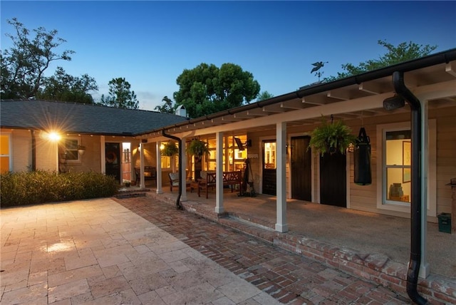 back house at dusk featuring a patio area