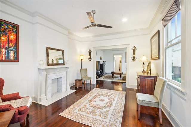 living area with ceiling fan, a premium fireplace, dark hardwood / wood-style flooring, and crown molding