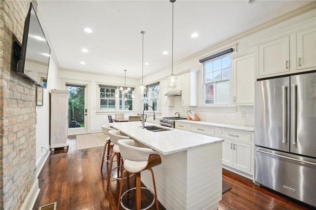 kitchen with appliances with stainless steel finishes, sink, white cabinetry, and a center island with sink