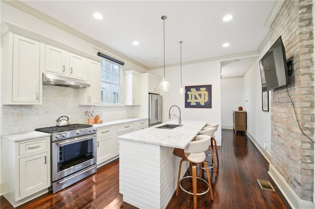 kitchen with high quality appliances, dark wood-type flooring, sink, hanging light fixtures, and white cabinetry